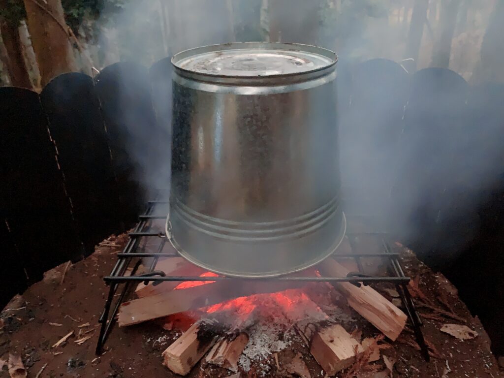 ビア缶チキンの作り方はキャンプ当日、火が安定したらチキンをビールを半分くらい残した缶をセットしたビア缶チキンスタンドに刺して、火の上に置いて、バケツを被せて40分から1時間程度焼く。
