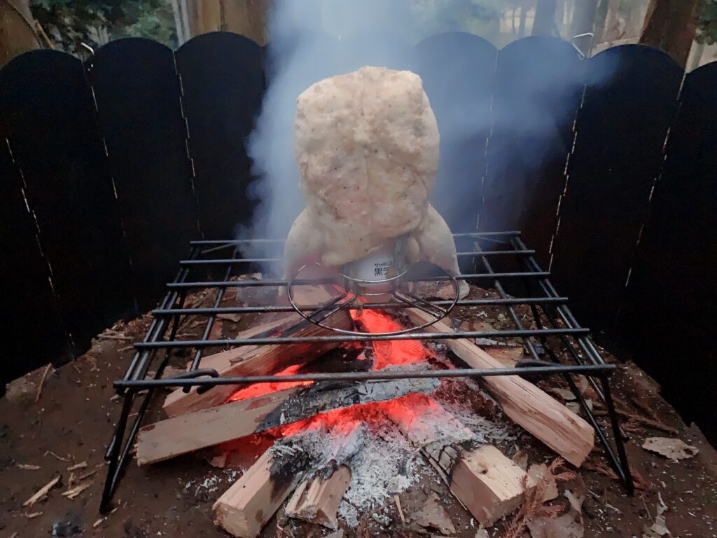 ビア缶チキンの作り方はキャンプ当日、火が安定したらチキンをビールを半分くらい残した缶をセットしたビア缶チキンスタンドに刺して、火の上に置く。