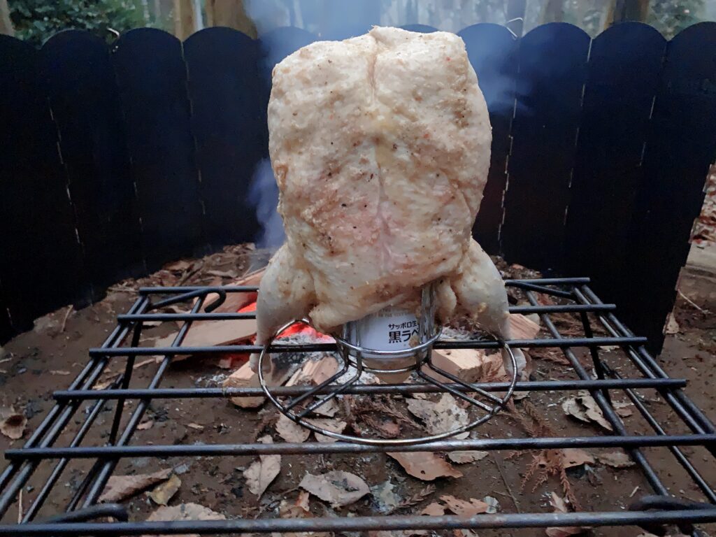 ビア缶チキンの作り方はキャンプ当日、火が安定したらチキンをビールを半分くらい残した缶をセットしたビア缶チキンスタンドに刺す。